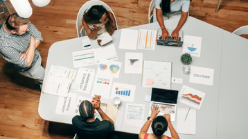 Equipe de marketing reunida desenvolvendo estratégia de SEO on page com gráficos e análise de dados sobre a mesa