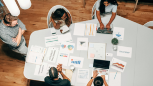 Equipe de marketing reunida desenvolvendo estratégia de SEO on page com gráficos e análise de dados sobre a mesa