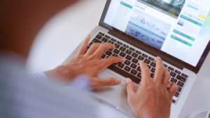 Pessoa digitando em um laptop com site aberto na tela, representando o trabalho com marketing digital e criação de conteúdo.