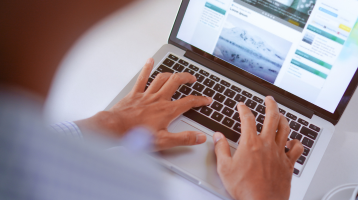 Pessoa digitando em um laptop com site aberto na tela, representando o trabalho com marketing digital e criação de conteúdo.