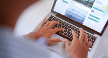 Pessoa digitando em um laptop com site aberto na tela, representando o trabalho com marketing digital e criação de conteúdo.